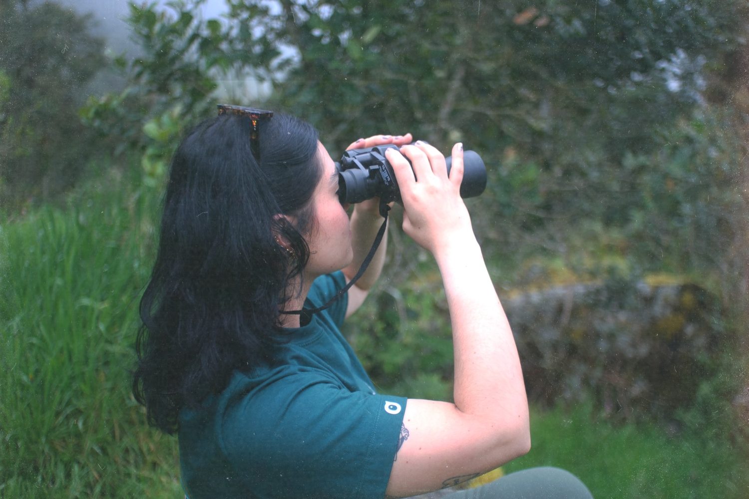 A birder in profile raising binoculars.